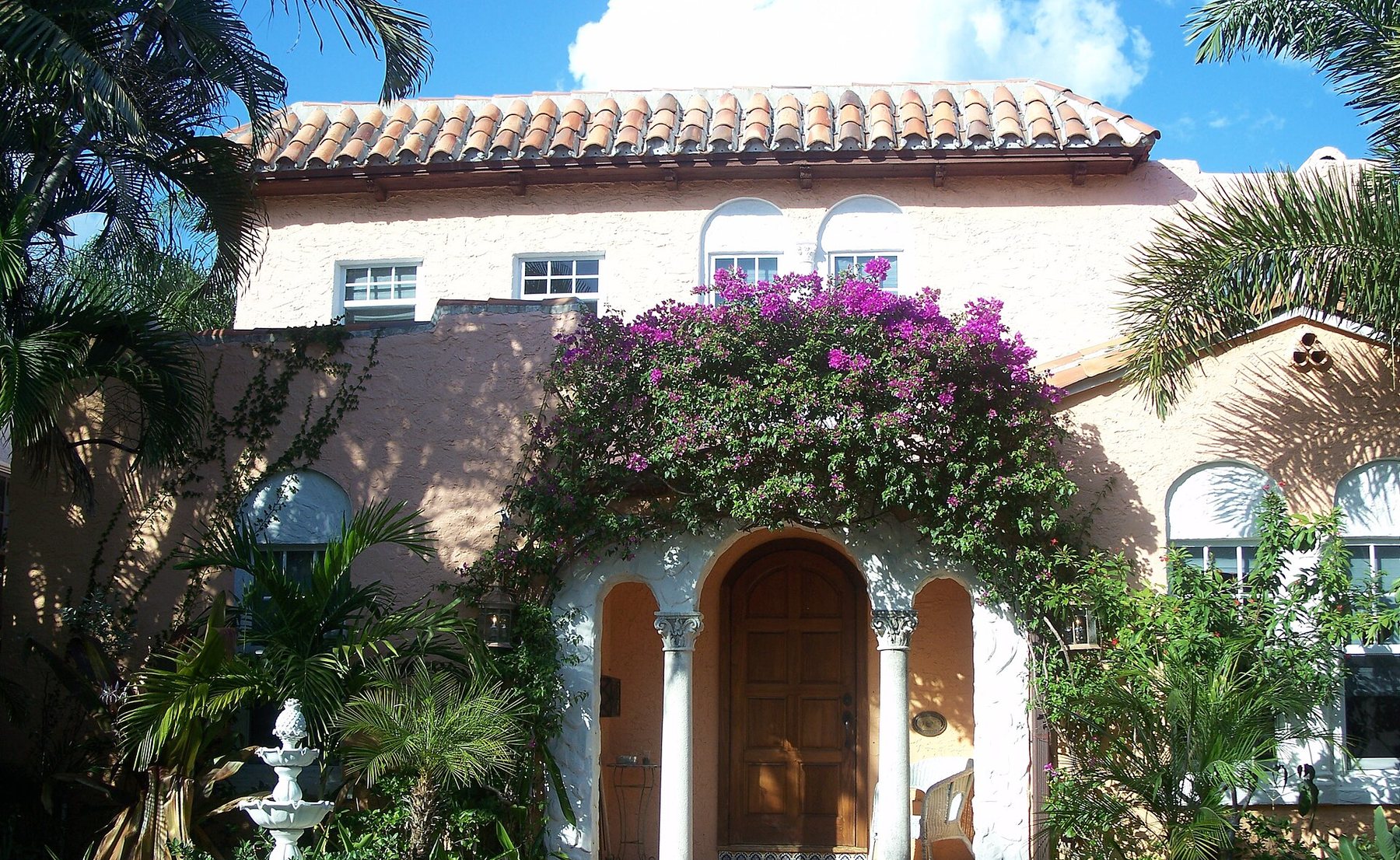 A Spanish-revival home in Tampa Bay, shaded by palms and bougainvillea.