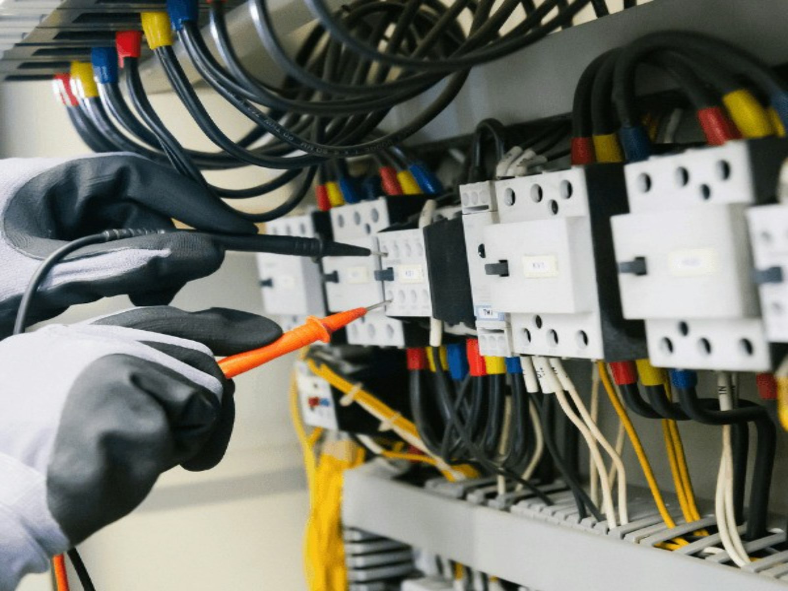 A technician testing wiring inside an electrical panel during a diagnostic visit.