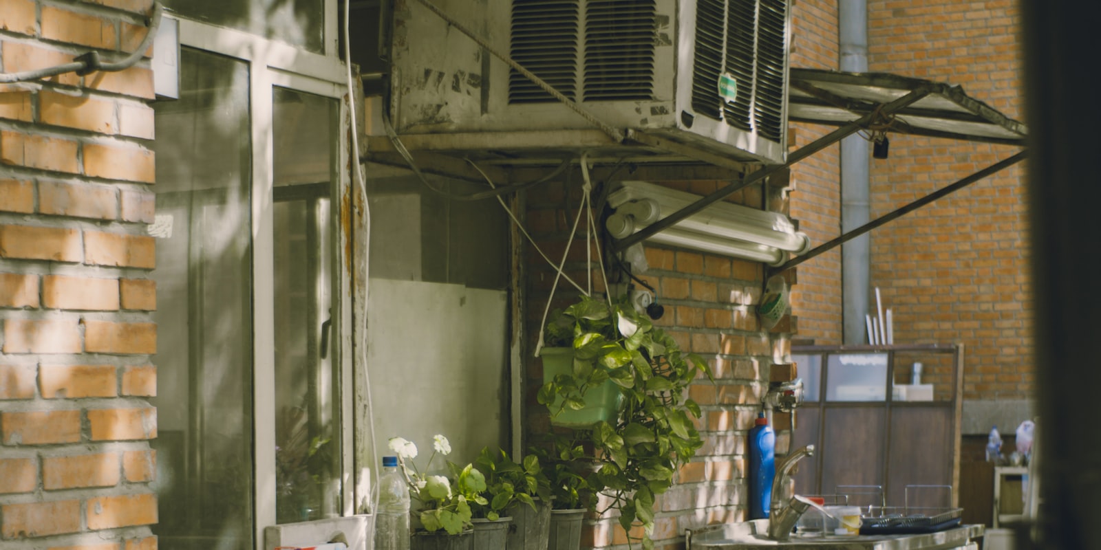 A weathered, aging outdoor condenser unit mounted on a wall.